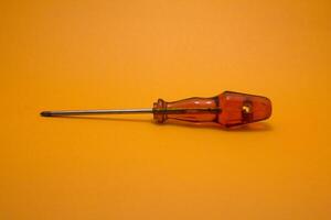 a red handle screwdriver isolated on yellow background photo