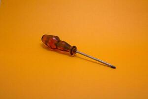 a red handle screwdriver isolated on yellow background photo