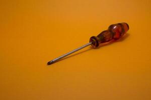 a red handle screwdriver isolated on yellow background photo