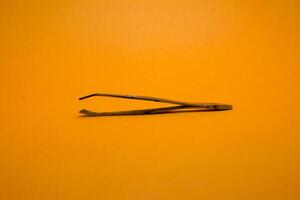 tweezers isolated on yellow background photo