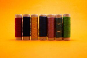 sewing thread roll isolated on yellow background photo