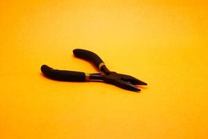 needle nose pliers isolated on yellow background photo