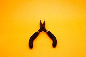 needle nose pliers isolated on yellow background photo