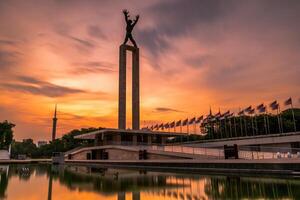 West Irian Liberation Monument in the Lapangan Banteng Bulls Field formerly Waterloo Square in Jakarta. Long exposure photography with beautiful golden sunrise. photo