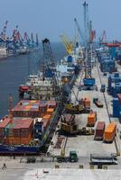 High angle view of business commercial port with cranes and logistics containers, cranes move the shipping container to unload logistics from cargo vessels photo