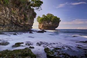 Beautiful scenery of rocky beach with cliffs and large waves in long exposure photography in Sawarna, Banten, Indonesia photo