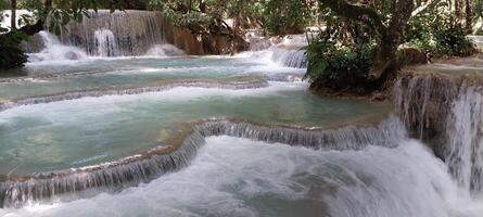 Scenic view of cascading waterfalls surrounded by lush greenery, creating serene natural pools in a tropical paradise. photo
