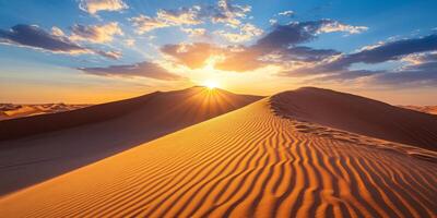 The sun setting behind towering dunes, casting long shadows across the desert photo