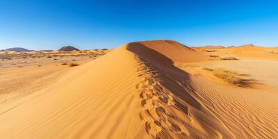 A single wind-sculpted sand dune in the vast desert, clear blue sky above photo