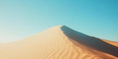 A single wind-sculpted sand dune in the vast desert, clear blue sky above photo