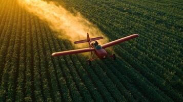 A red crop duster plane flies over a field of green crops, spraying a fine mist. photo