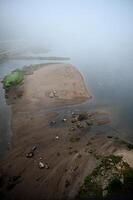 a body of water with a sand beach and a foggy shore photo
