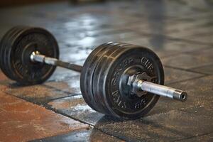 Black barbell resting on gym floor after strength training workout photo