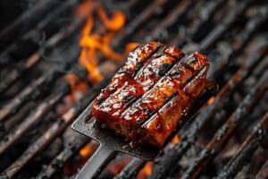 Barbecue spatula holding grilled meat over hot coals photo
