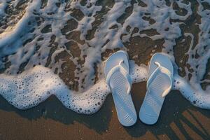 White flip flops washing up on the beach shore photo