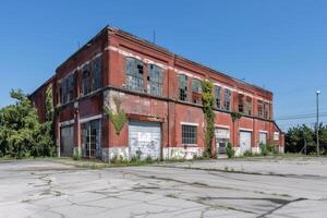 Abandoned red brick industrial building crumbling with broken windows photo
