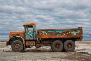 Old rusty abandoned dump truck under cloudy sky photo
