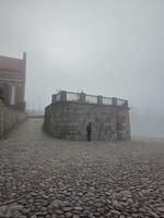 a person standing on a stone path in the fog photo