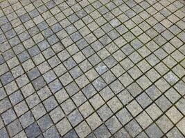 a tiled floor with grass growing on it photo