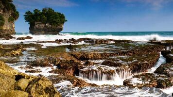 The beauty of Karang Bokor Beach, Sawarna, Banten. Large rock decorated with trees in the middle of the sea are the main attraction of this view with the crashing waves add to the dynamic impression. photo