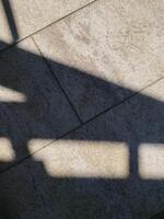 Shadows on textured stone surface, abstract geometric pattern. Light and shadow, contrast, composition. Minimalist, everyday materials. Ideal for backgrounds or textures photo