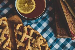 Rustic apple pie with a fresh lemon tea on a plaid tablecloth for autumn photo