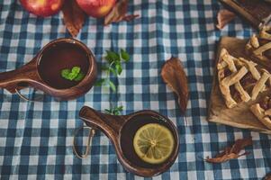 Rustic autumn table setting with hot beverages and pie on a blue checkered tablecloth photo