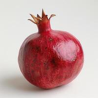 a red pomegranate on a white surface photo