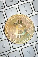 Bitcoin coin resting on the computer keyboard photo