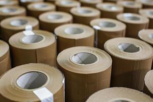 Rolls of brown paper are stacked in a warehouse, creating a satisfying pattern photo