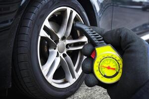 Check tire pressure , auto mechanic is holding a tire pressure gauge to check tire pressure , Car maintenance concept photo