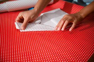 Hands carefully folding polka dot wrapping paper in preparation for gift wrapping, creating a beautifully wrapped present with precision and attention to detail for a special occasion or event. photo