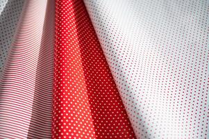 Colorful red and white polka dot and striped pattern paper with light and shadows creating a cheerful and festive atmosphere. photo