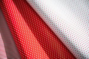 Close-up of red and white polka dot and striped wrapping paper rolls overlapping each other, creating a festive and vibrant pattern ideal for gift wrapping, crafts, or holiday decorations. photo