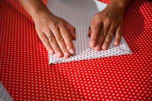 Hands folding red polka dot paper for a festive look in holiday gift wrapping and DIY projects photo