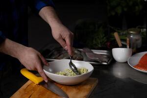 Person mixing fresh ingredients in bowl. Kitchen setting includes various food items and utensils, indicating active meal preparation photo