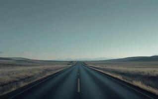 A long, straight road cuts through a vast prairie landscape with distant mountains on the horizon, showcasing the beauty of open spaces and solitude photo