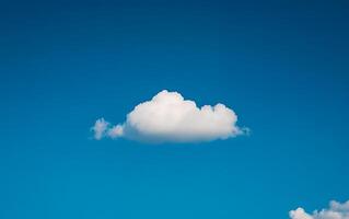 A single, perfectly formed fluffy white cumulus cloud floating in a clear, vibrant blue sky, symbolizing peace, freedom, and possibility photo