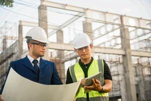 Engineer and architect monitor the progress of building construction plan and verify their accuracy. photo
