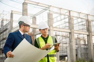 Engineer and architect monitor the progress of building construction plan and verify their accuracy. photo