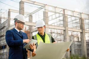 Engineer and architect monitor the progress of building construction plan and verify their accuracy. photo