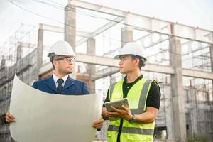 Engineer and architect monitor the progress of building construction plan and verify their accuracy. photo