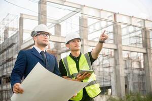 Engineer and architect monitor the progress of building construction plan and verify their accuracy. photo
