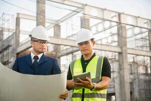 Engineer and architect monitor the progress of building construction plan and verify their accuracy. photo