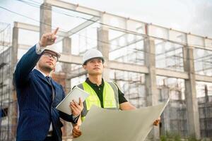 Engineer and architect monitor the progress of building construction plan and verify their accuracy. photo