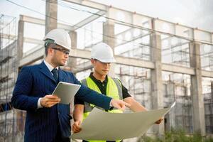 Engineer and architect monitor the progress of building construction plan and verify their accuracy. photo