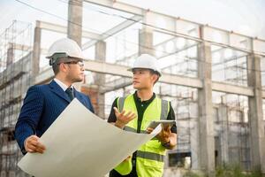Engineer and architect monitor the progress of building construction plan and verify their accuracy. photo