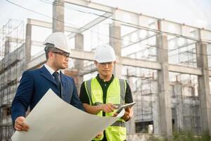 Engineer and architect monitor the progress of building construction plan and verify their accuracy. photo