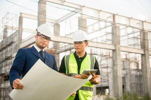 Engineer and architect monitor the progress of building construction plan and verify their accuracy. photo