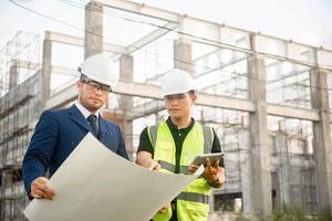 Engineer and architect monitor the progress of building construction plan and verify their accuracy. photo